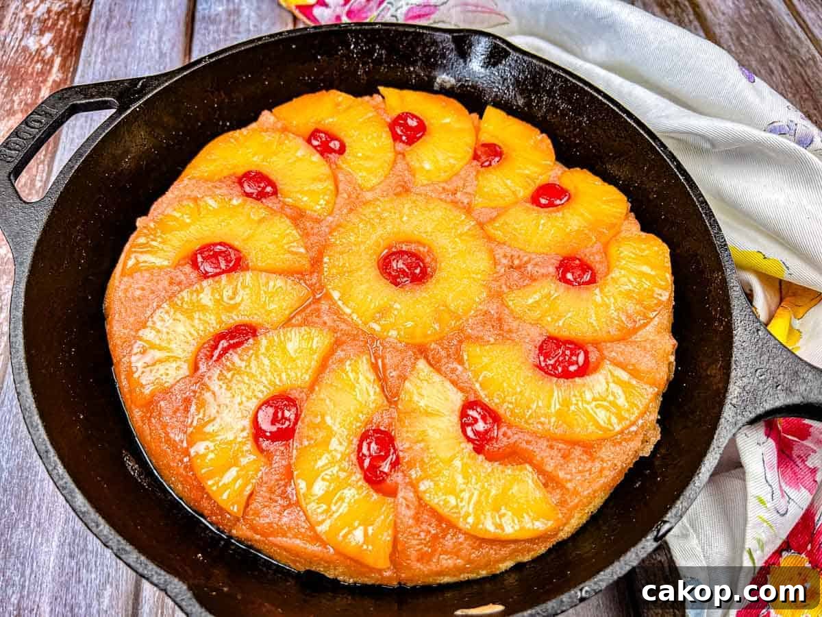 A pineapple upside-down cake with cherry toppings in a cast iron skillet.
