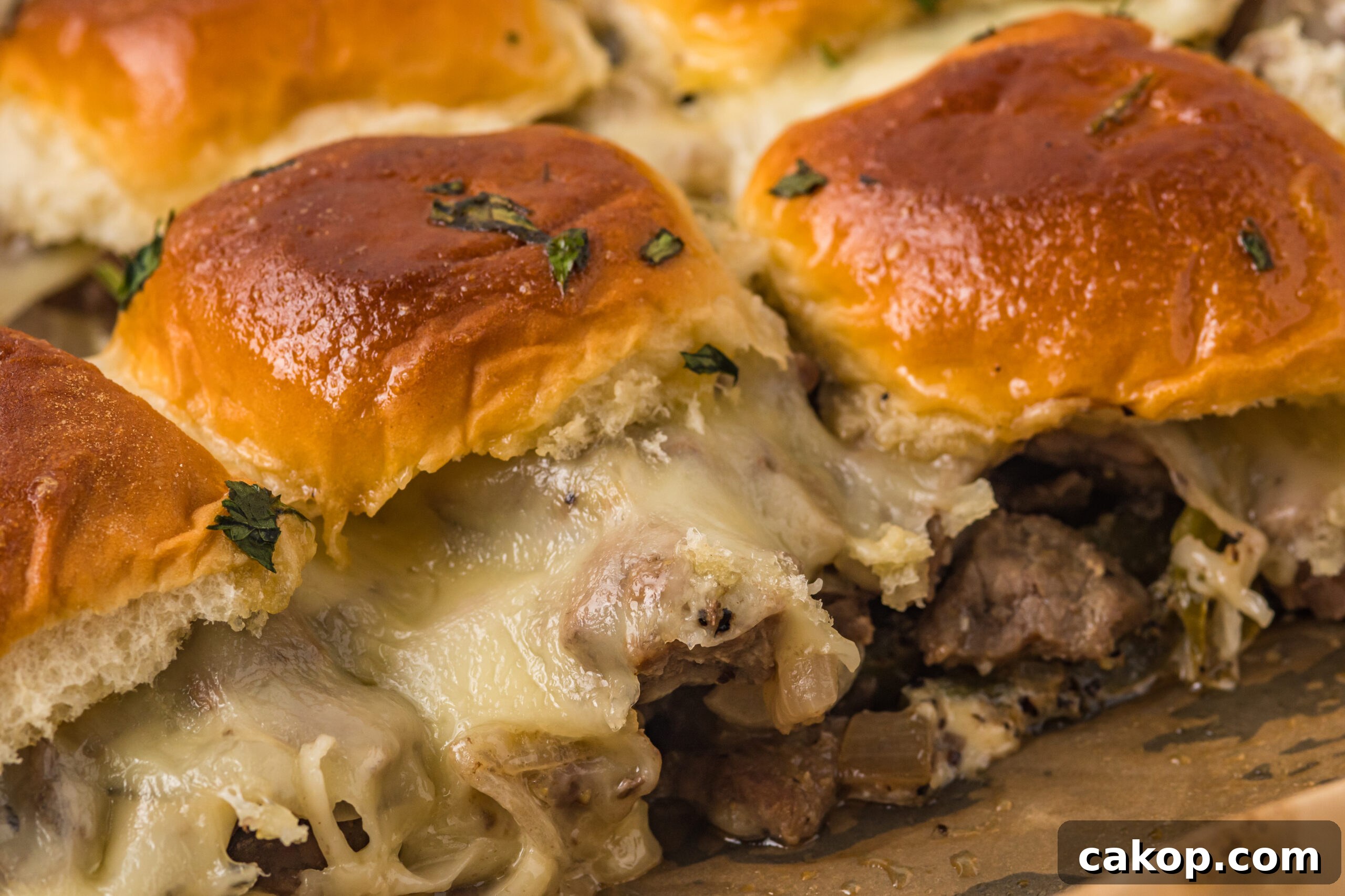 Philly Cheesesteak Sliders Recipe: Savory Mini Sandwiches for Game Day 11 Philly Cheesesteak Sliders on a baking sheet up close to see melty cheese and texture.