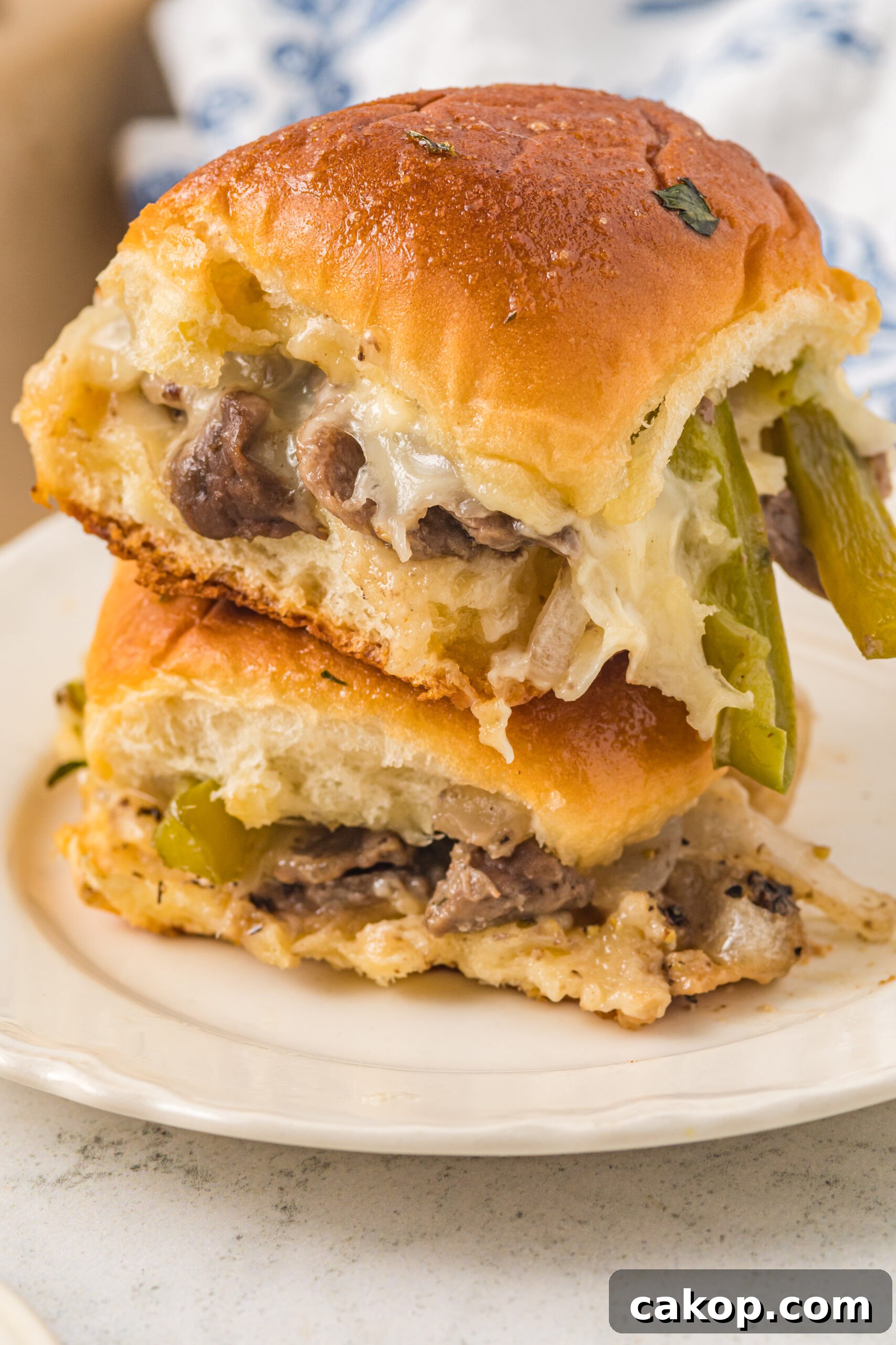 Philly Cheesesteak Sliders Recipe: Savory Mini Sandwiches for Game Day 12 Two sliders stacked on a white plate.