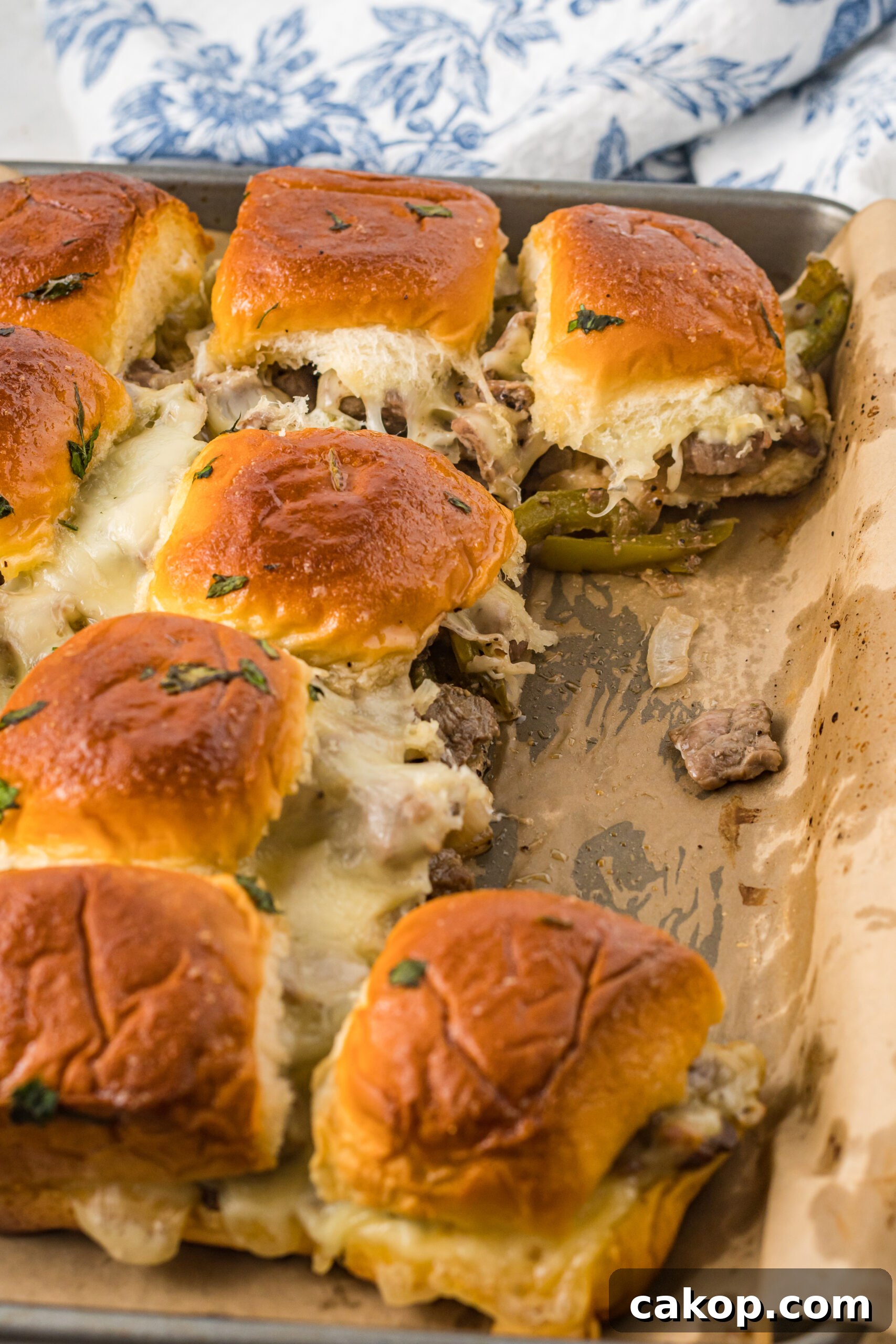 Philly Cheesesteak Sliders Recipe: Savory Mini Sandwiches for Game Day 3 Philly Cheesesteak Sliders on a baking sheet with two removed.