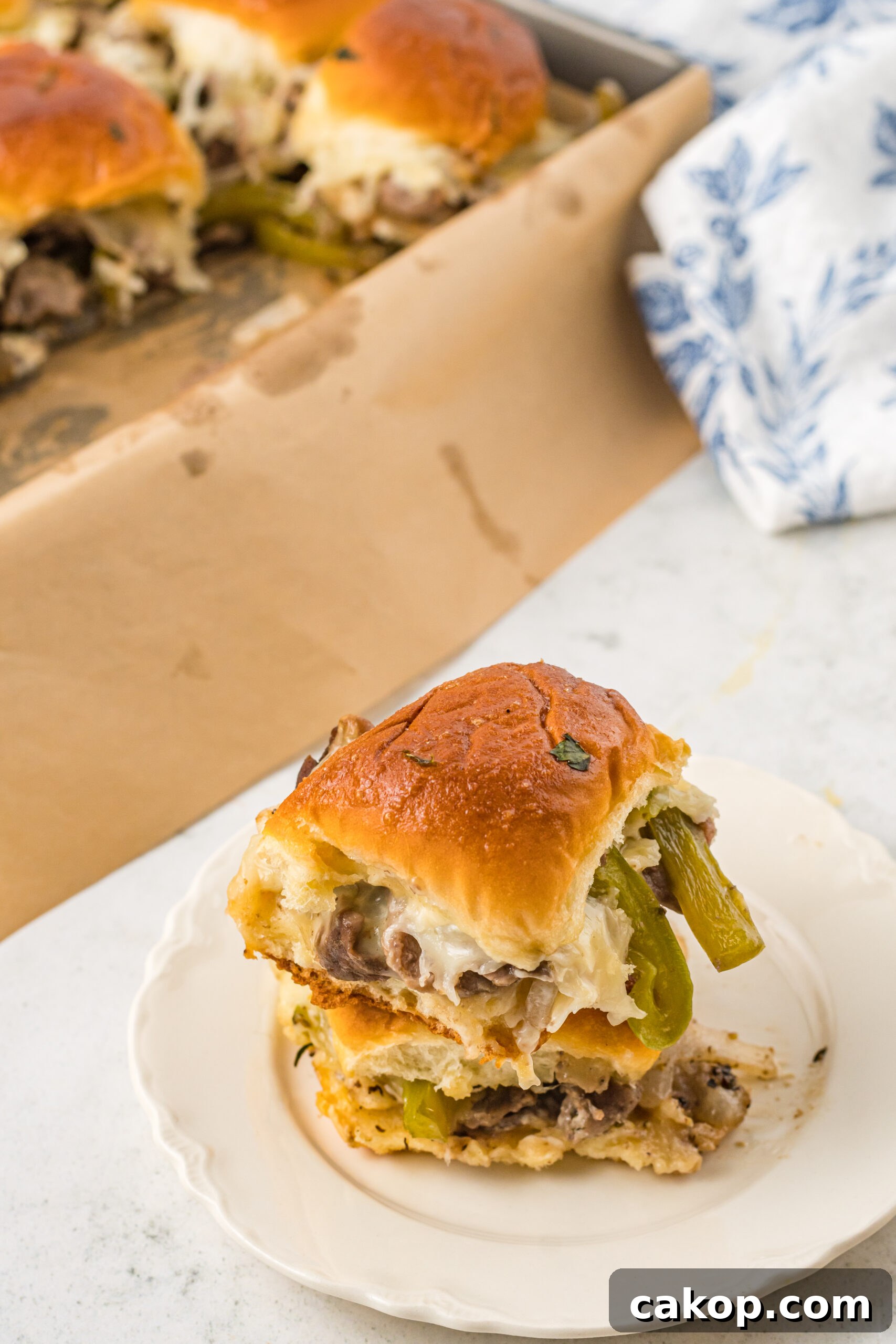Philly Cheesesteak Sliders Recipe: Savory Mini Sandwiches for Game Day 4 Two sliders stacked on a white plate.