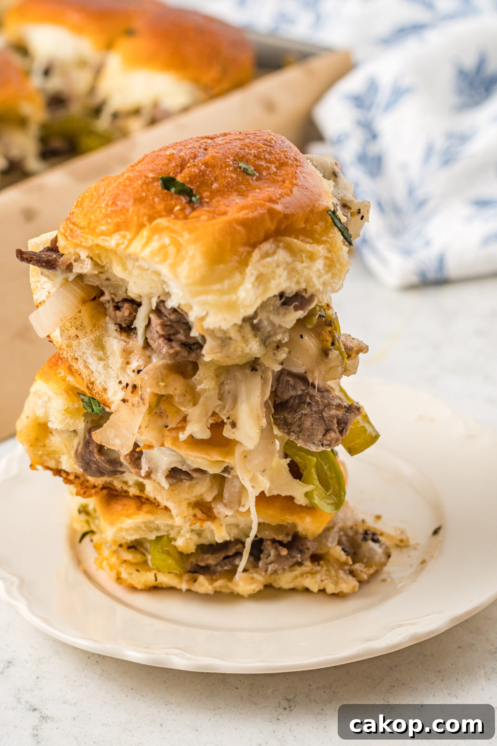 Philly Cheesesteak Sliders Recipe: Savory Mini Sandwiches for Game Day 5 Three sliders stacked on a white plate.