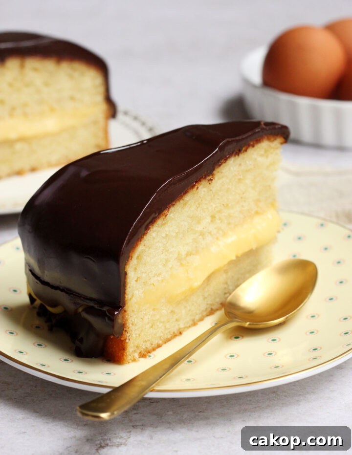 Classic Boston Cream Pie Recipe: Creamy Custard & Chocolate Glaze 9 slice of Boston cream pie on a plate