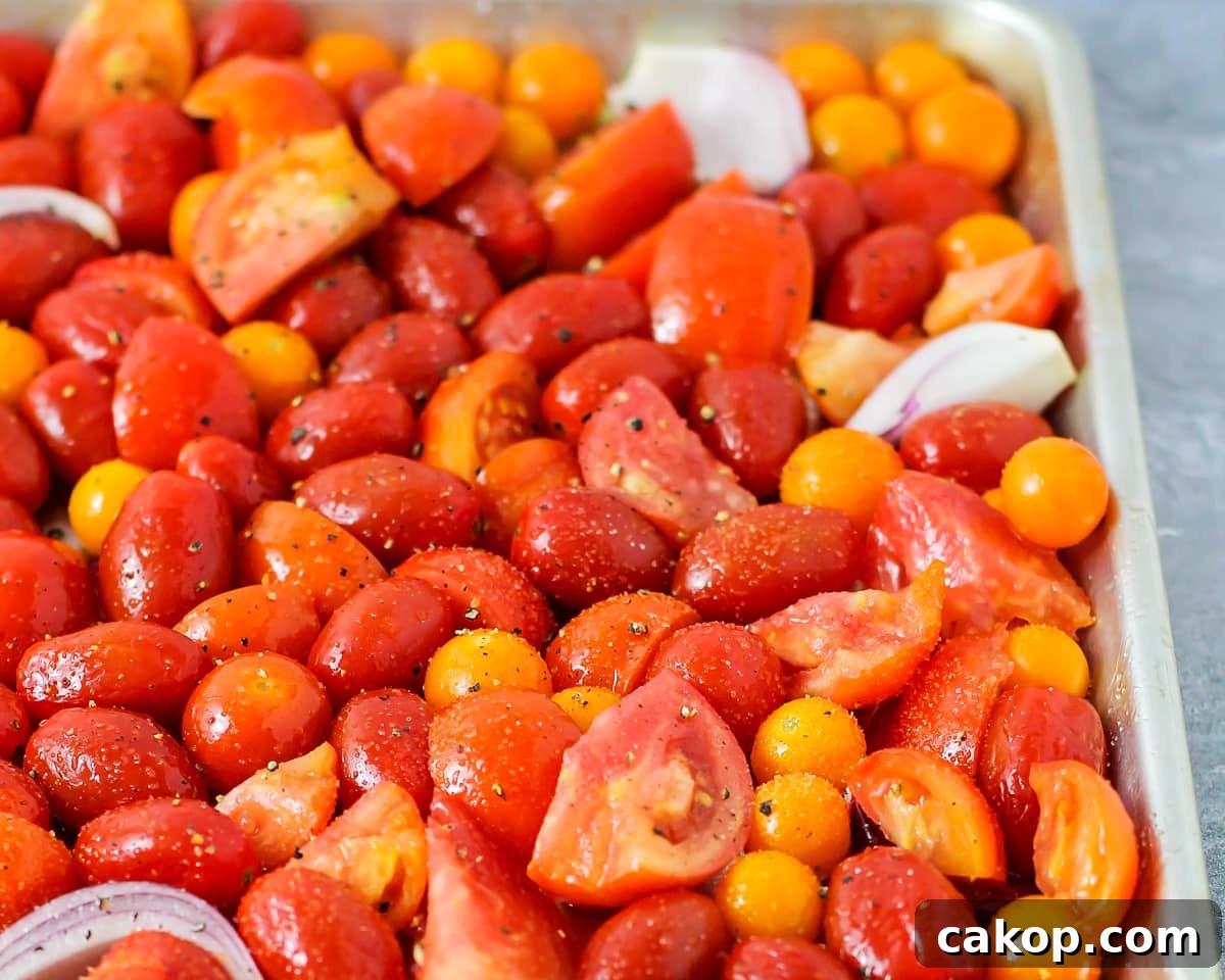 Tomatoes sliced and seasoned and spread on a baking sheet.
