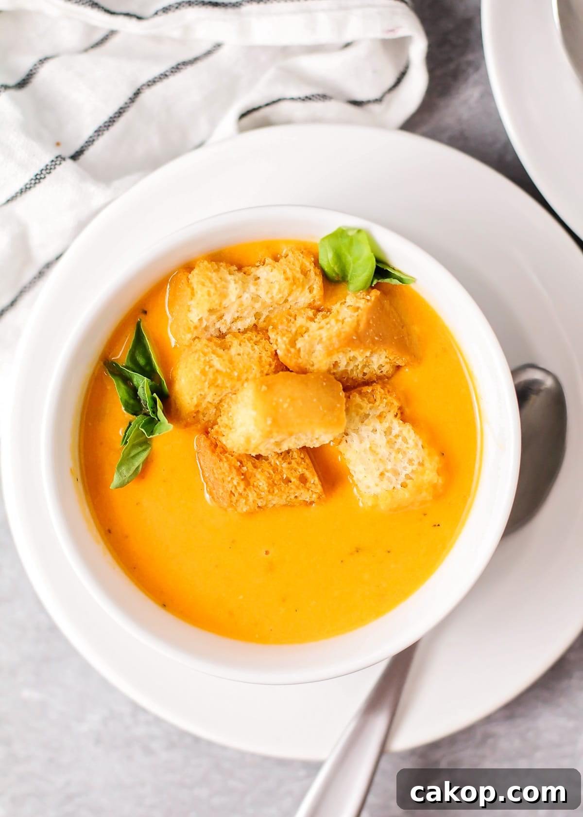 Roasted tomato soup served in a white bowl and topped with croutons.