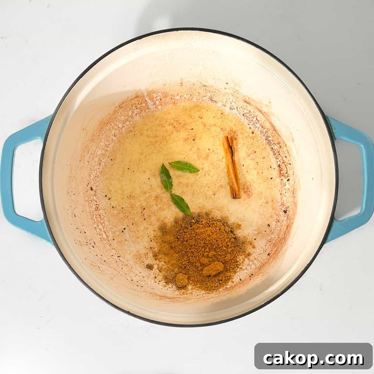 Adding the bay leaves and curry powder to the butter in a large saucepan.