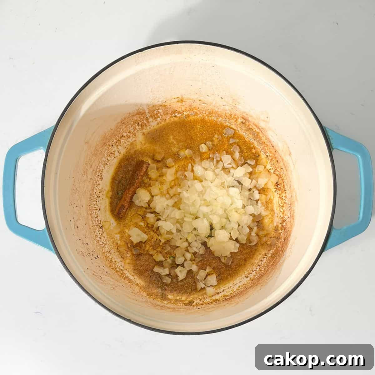 Adding onions to the hot oil for the beef curry with coconut milk.