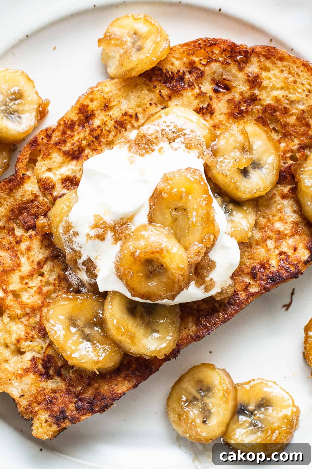 Bananas Foster French Toast Recipe for Brunch or Dessert 2 A plate of french toast with banana slices and whipped cream.