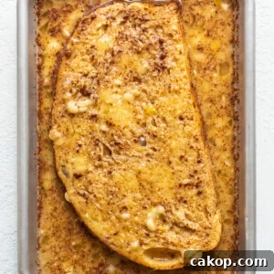 Bananas Foster French Toast Recipe for Brunch or Dessert 9 A slice of french toast in a pan on a white surface.