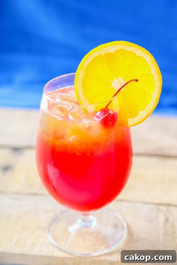 a hurricane cocktail garnished with an orange slice and a maraschino cherry.
