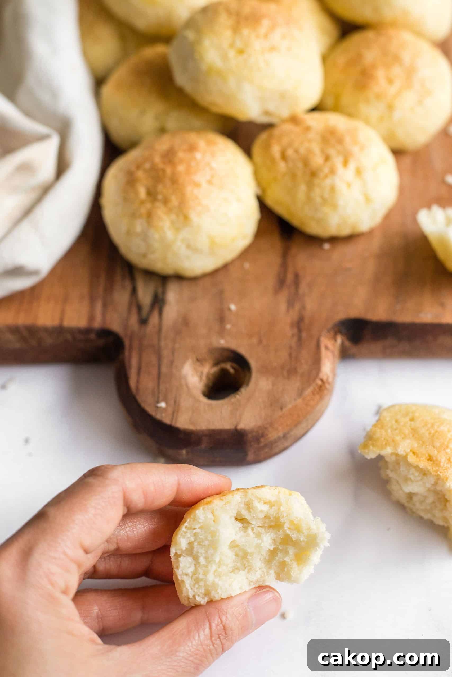 GF Dinner Rolls (Dairy-Free) Hand holding a torn half of a gluten-free roll.