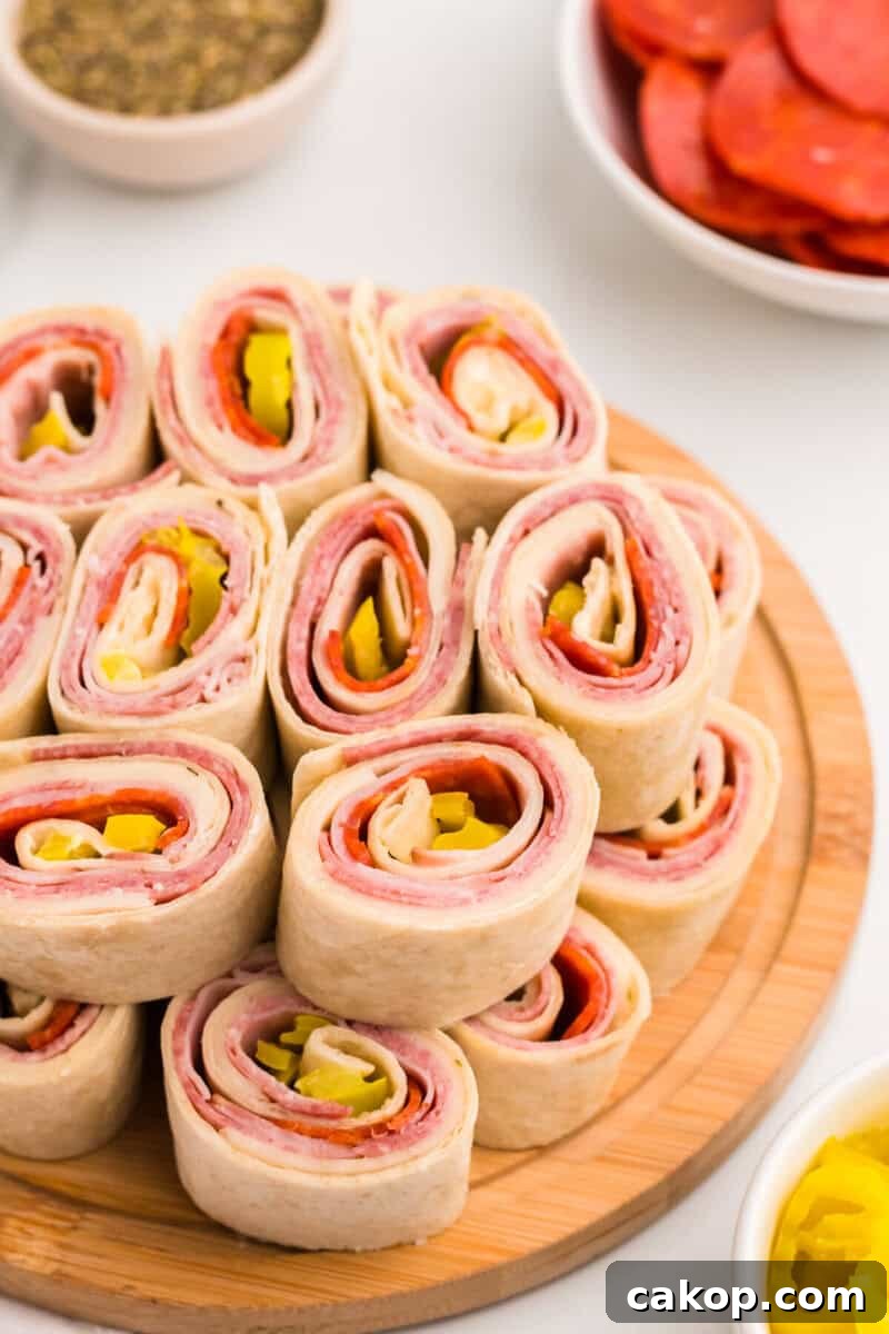 Italian Pinwheels stacked on top of each other on a wooden serving board.