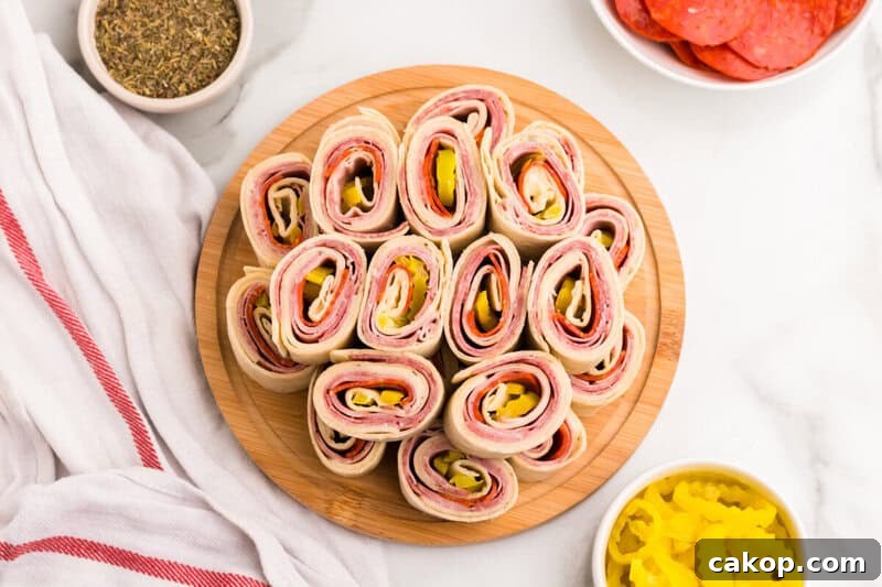 Italian Pinwheels stacked on top of each other on wooden serving board.