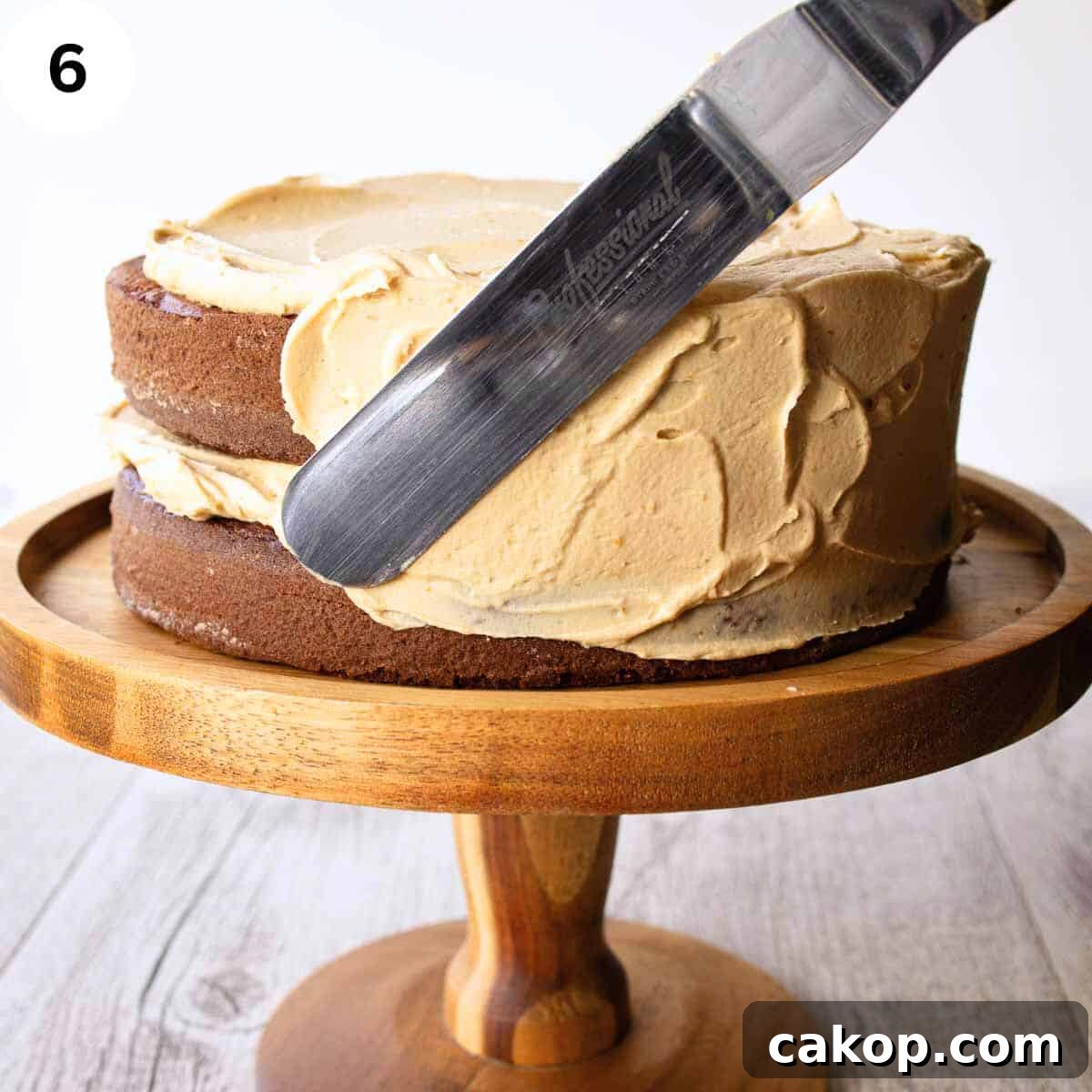 Decadent Chocolate Peanut Butter Cake Recipe 9 Spreading buttercream on the side of a two layer cake.