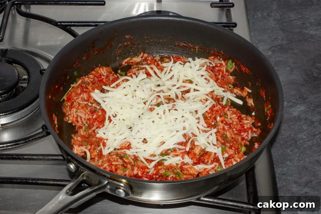 Rice stuffed peppers filling in a pan with grated mozzarella on top