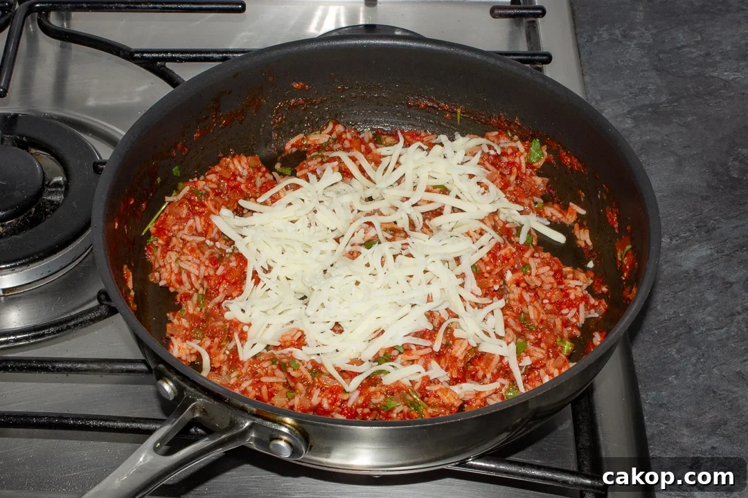 Rice stuffed peppers filling in a pan with grated mozzarella on top