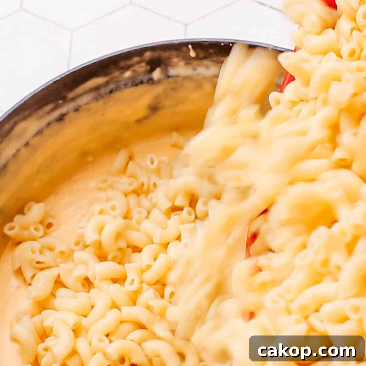 Combining cheese sauce and cooked macaroni.