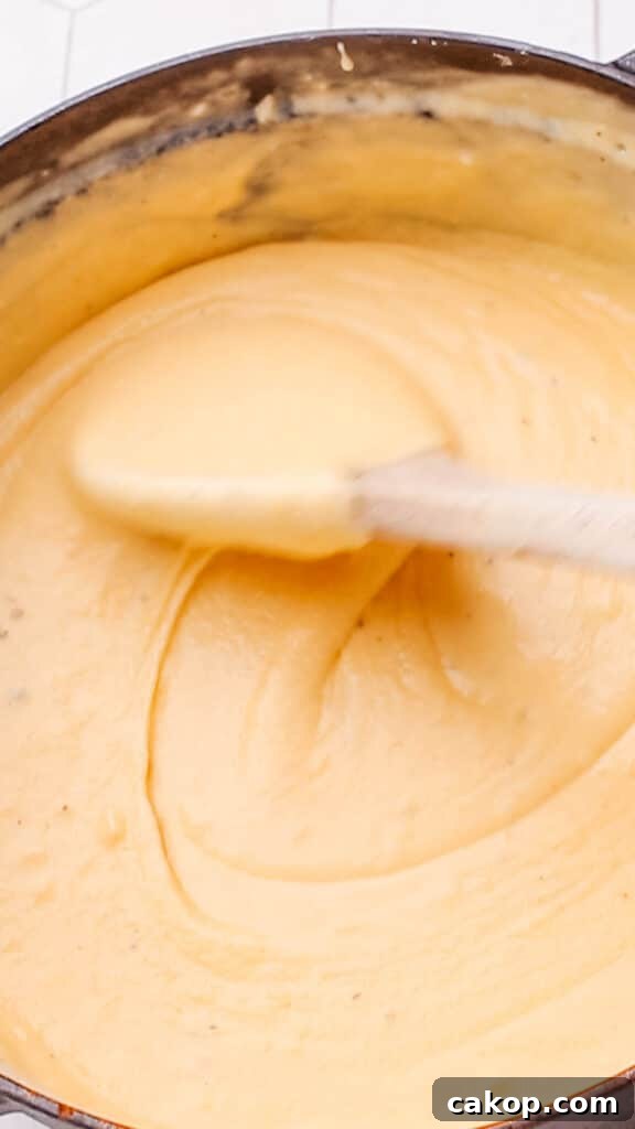 Stirring cheddar cheese sauce for macaroni and cheese.