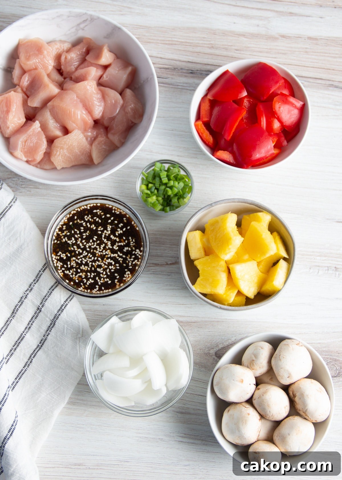 Grilled Teriyaki Chicken and Pineapple Kabobs Recipe 8 Picture of cut up ingredients in bowls. Chicken, pineapple, mushrooms, peppers, onion, teriyaki sauce, green onions.