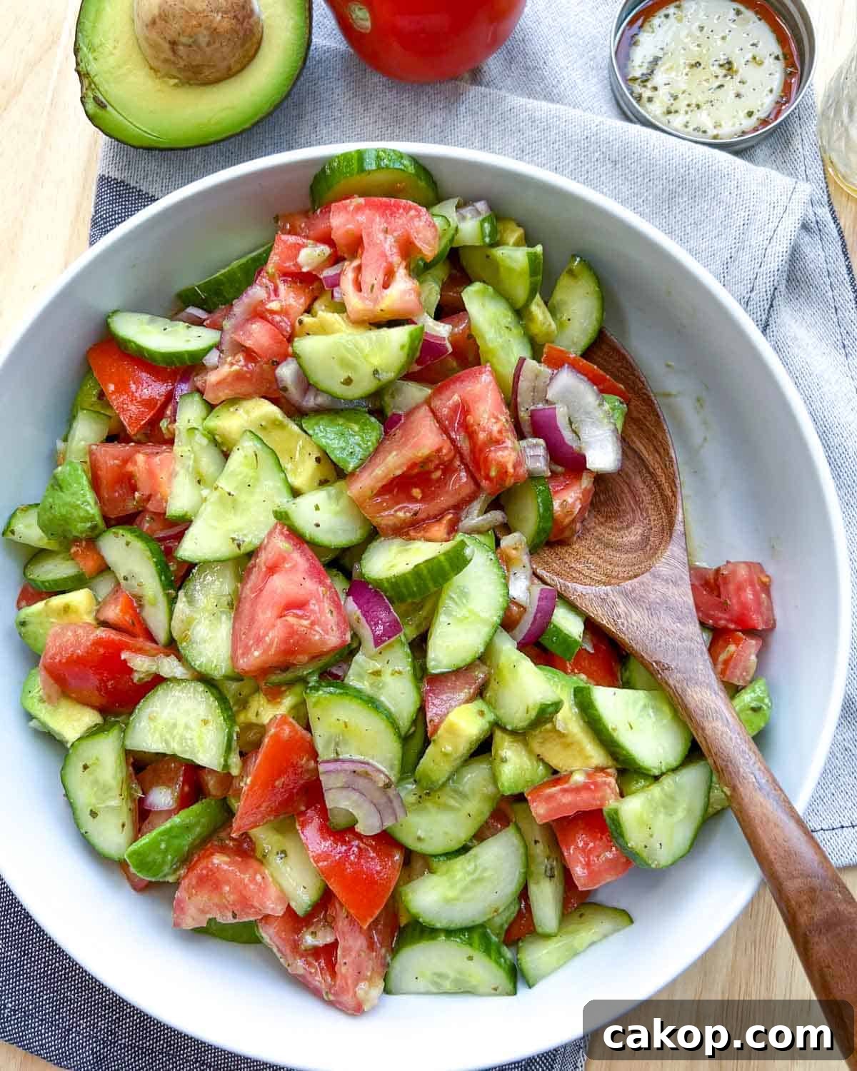 Creamy Avocado and Tomato Salad with Lime and Basil 11 wooden spoon in a white salad bowl.