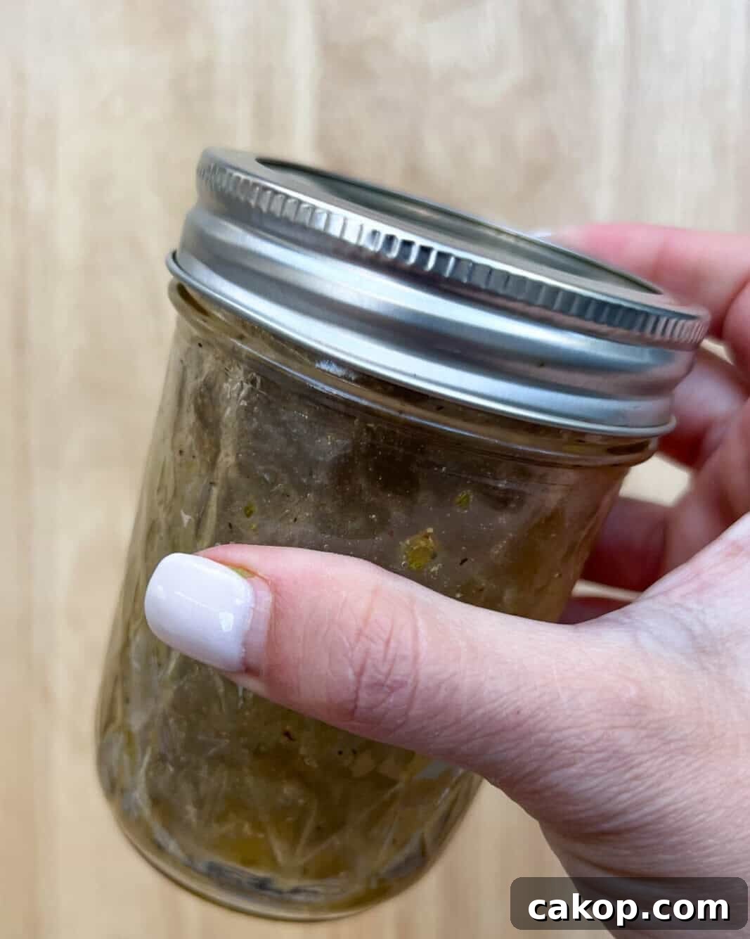 Creamy Avocado and Tomato Salad with Lime and Basil 6 Salad dressing ingredients mixed in a mason jar. Hand-holding jar.