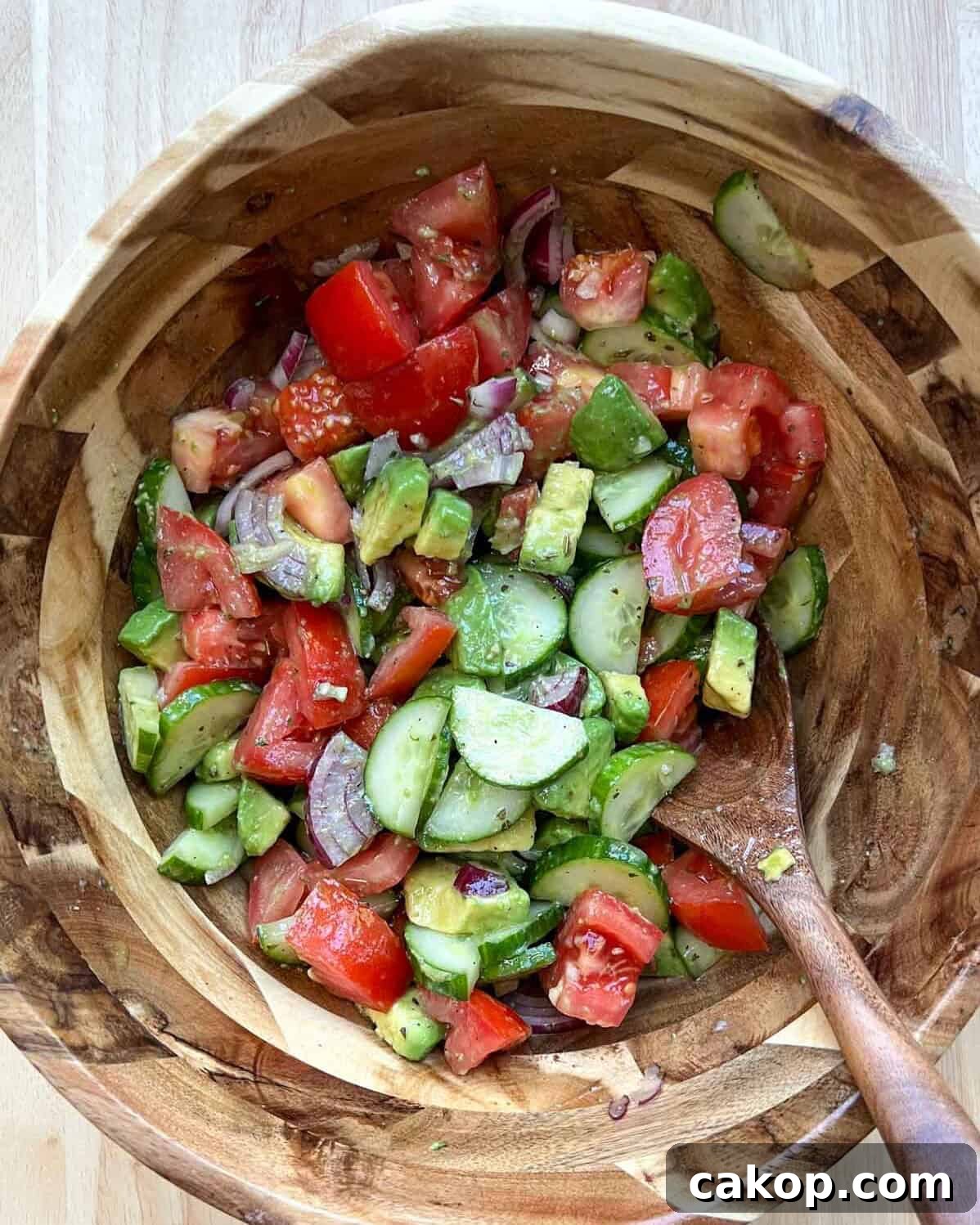 Creamy Avocado and Tomato Salad with Lime and Basil 9 salad ingredients mixed together in a wooden bowl.