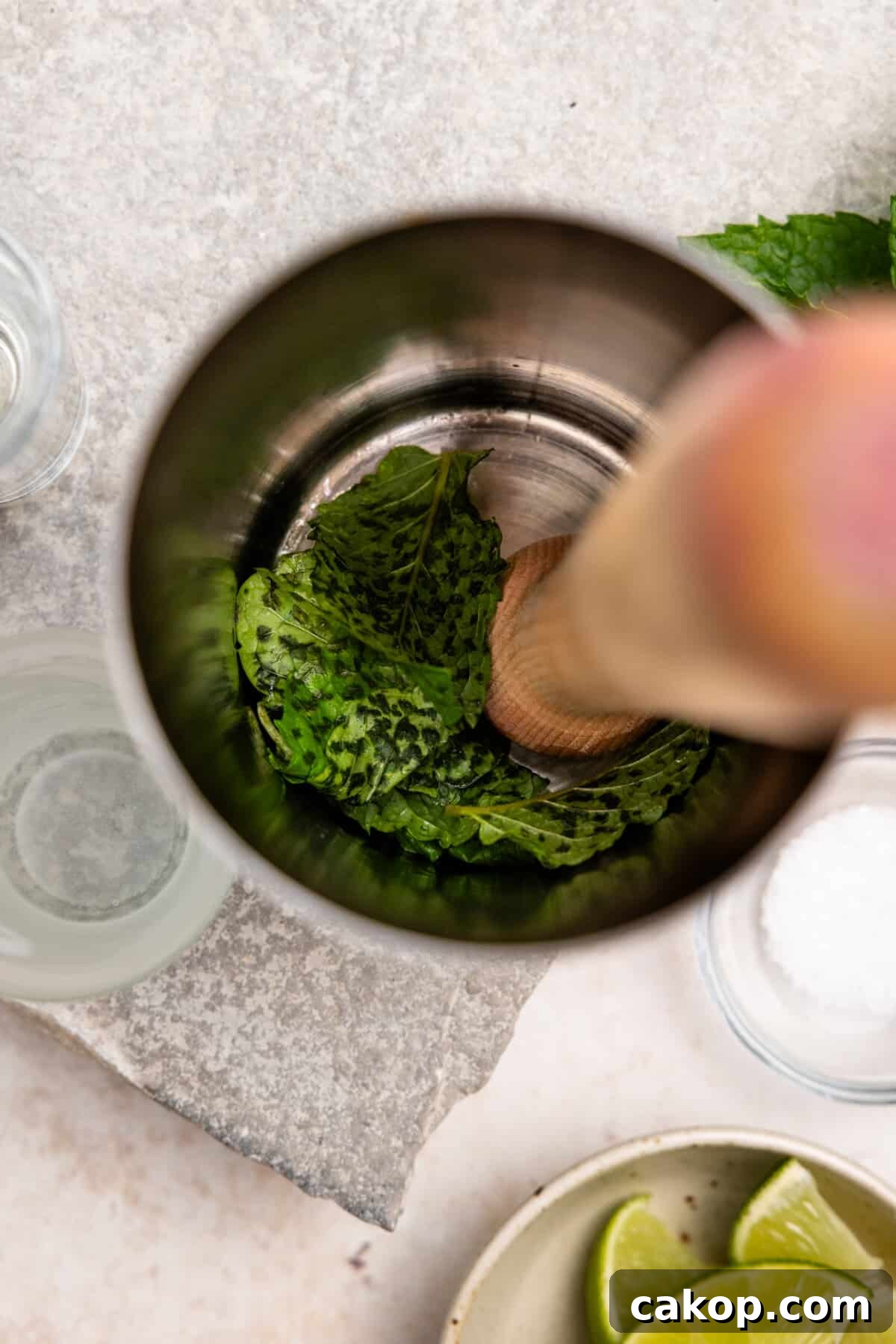 Muddling mint in a cocktail shaker.