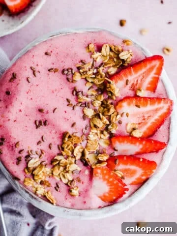 A pink smoothie bowl with fruit and granola.