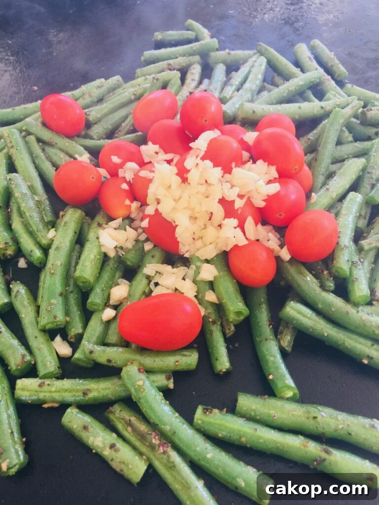 Blackstone Ribeye with Sautéed Garlic Green Beans 6 adding tomatoes and garlic to the griddle
