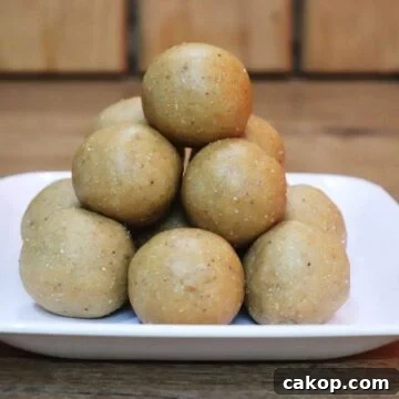 Peanut ladoos placed on a white plate on a brown counter top.