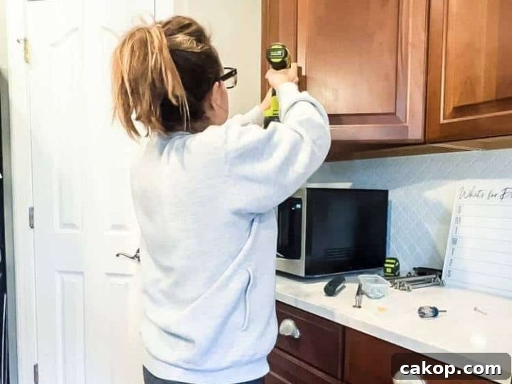 Woman using a jig template to drill holes for new kitchen cabinet handles