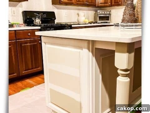 Kitchen with cherry cabinets & white quartz counters. The island is being painted with 3 different color swatches to choose
