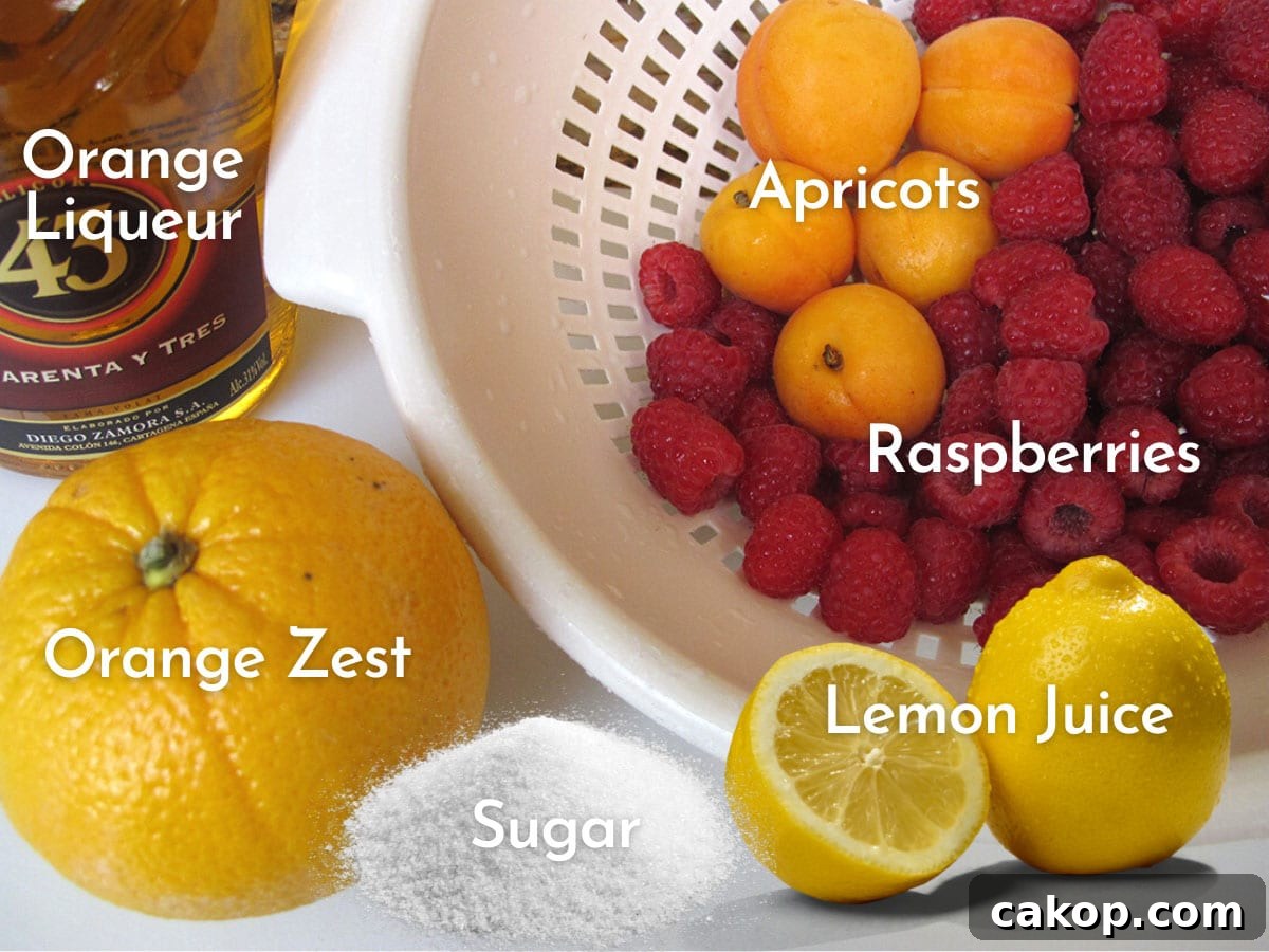 A colander filled with ripe apricot, fresh raspberries and to the side a fresh orange for zest and a bottle of Mexican liqueur called 43 with labels to describe in white.