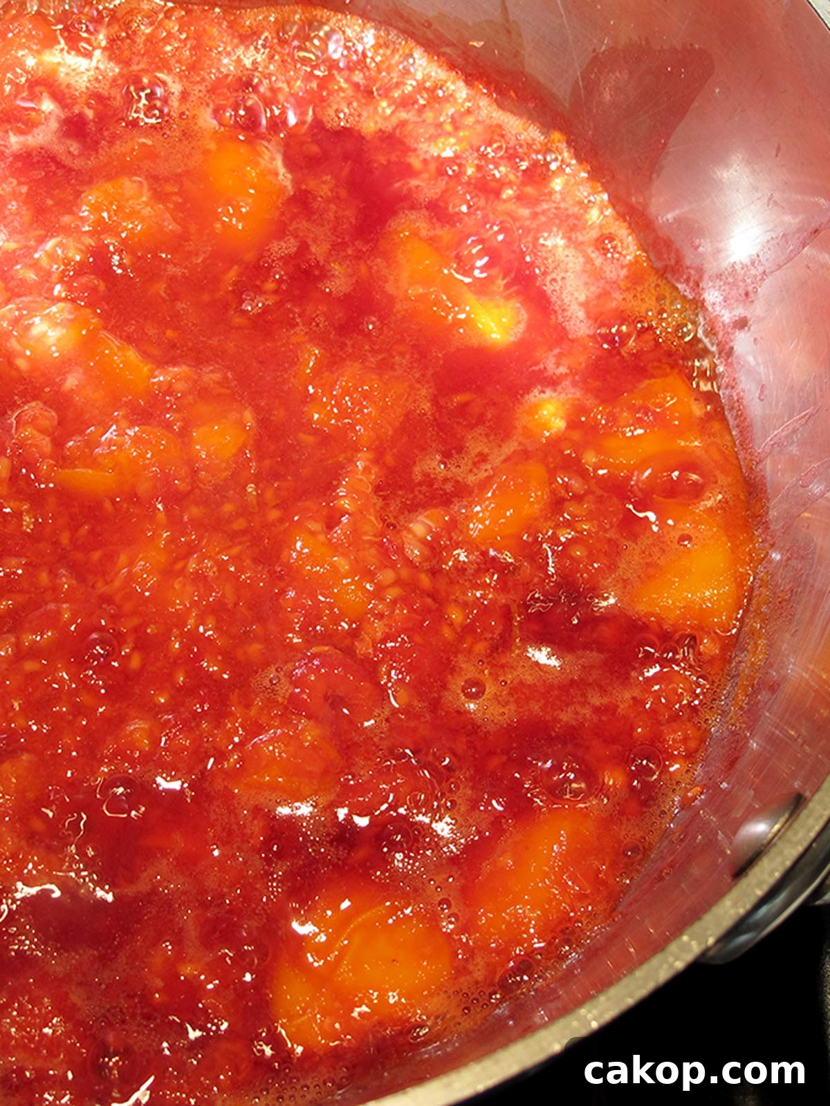 Apricots and raspberries bubbling in pot.