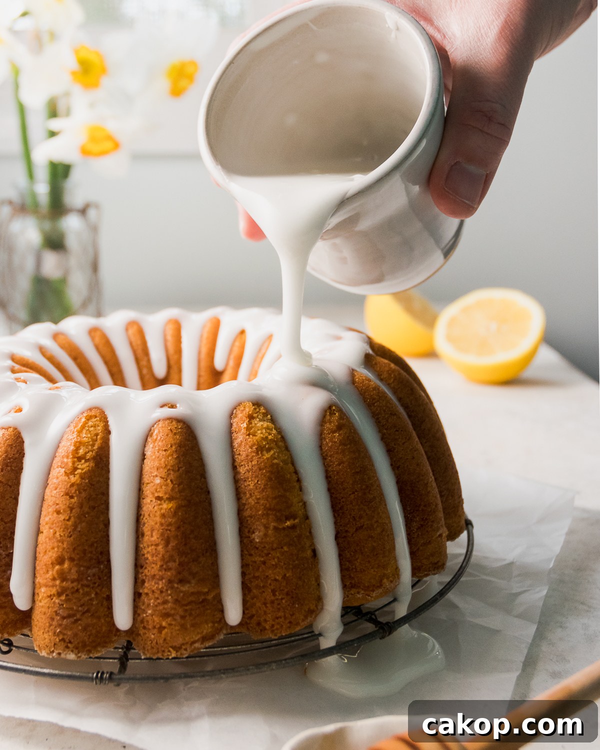 Glaze being poured over a gluten free lemon bundt cake.