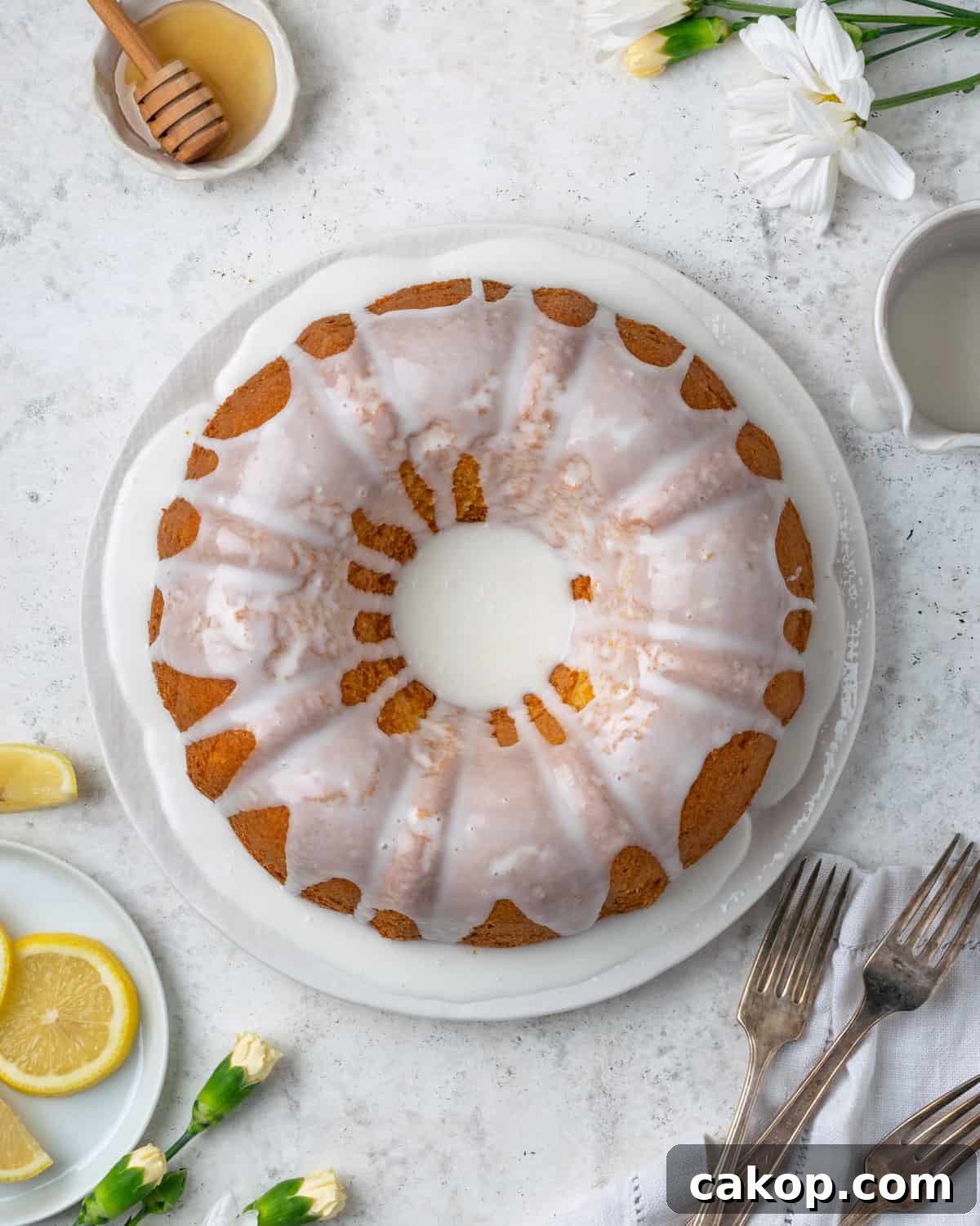 A gluten free lemon pound cake covered with white icing sitting on a table. 