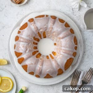 A lemon bundt cake topped with white icing served on a white plate.