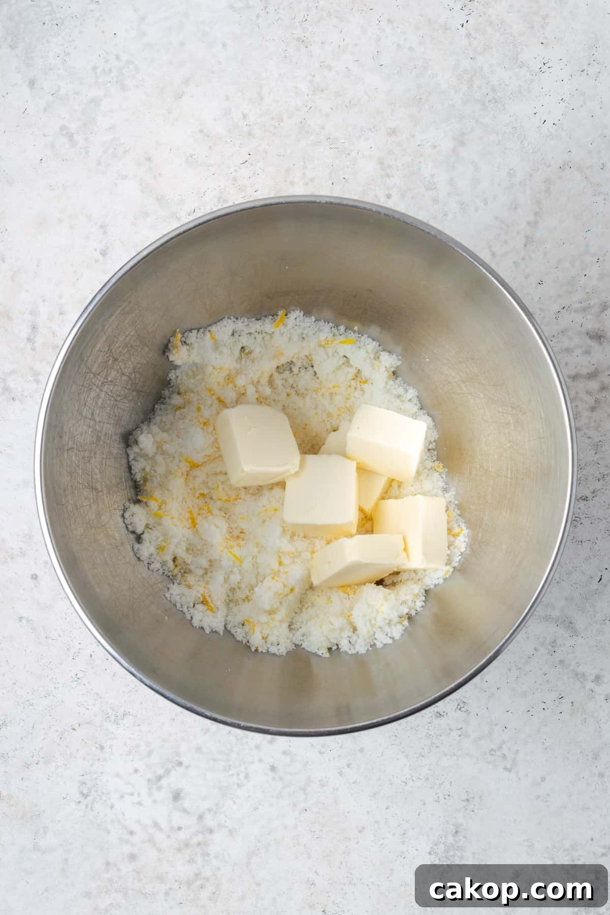 Sugar with lemon zest and butter in a large mixing bowl.