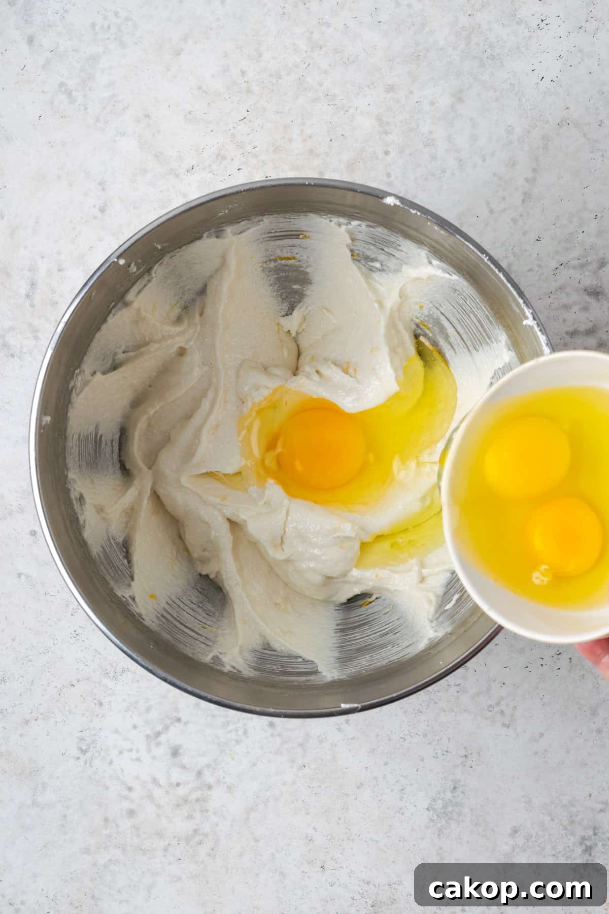Eggs being poured into the partially mixed cake batter.
