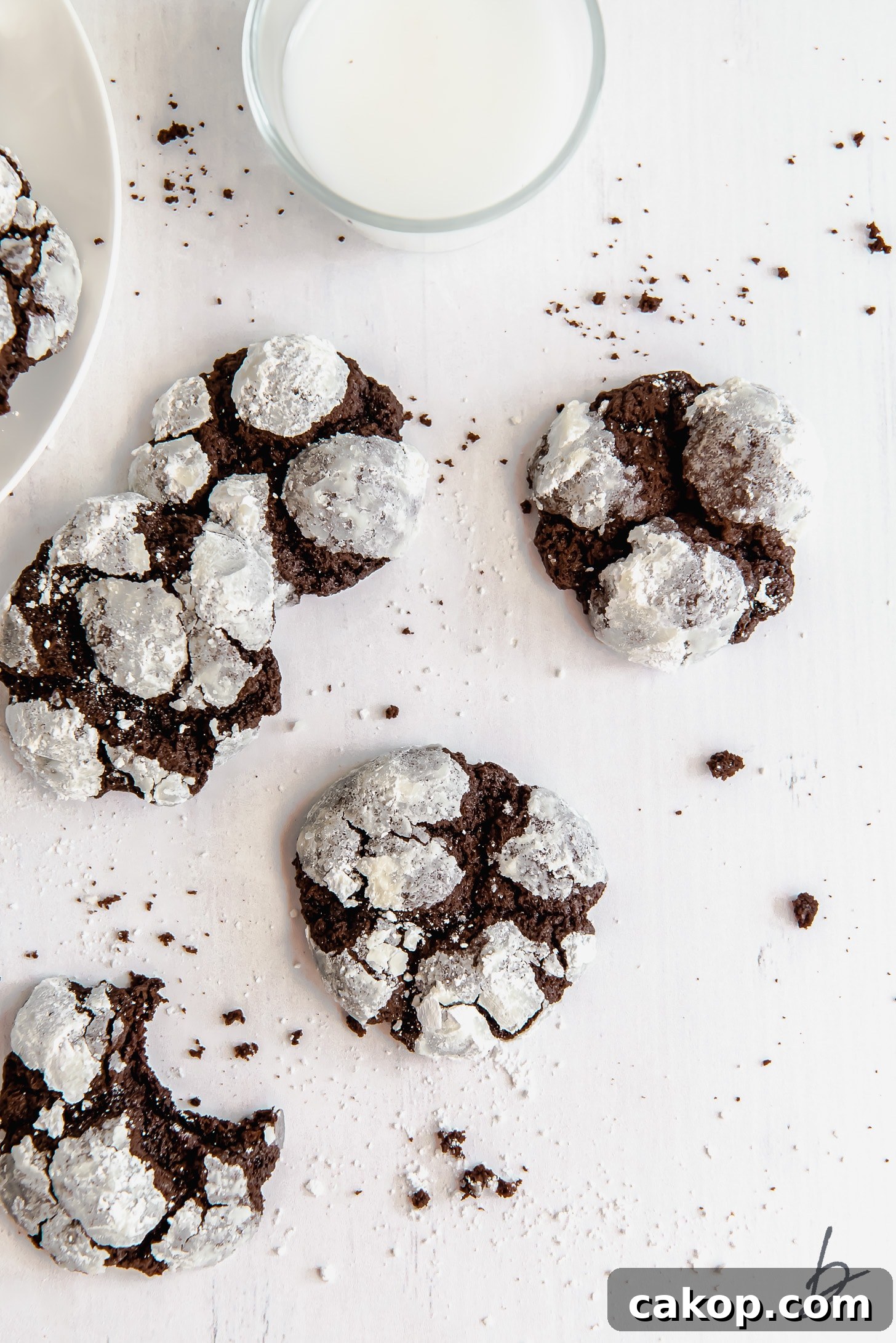Chewy Chocolate Crinkle Cookie Recipe 6 chocolate crinkle cookies on a white surface next to glass of milk