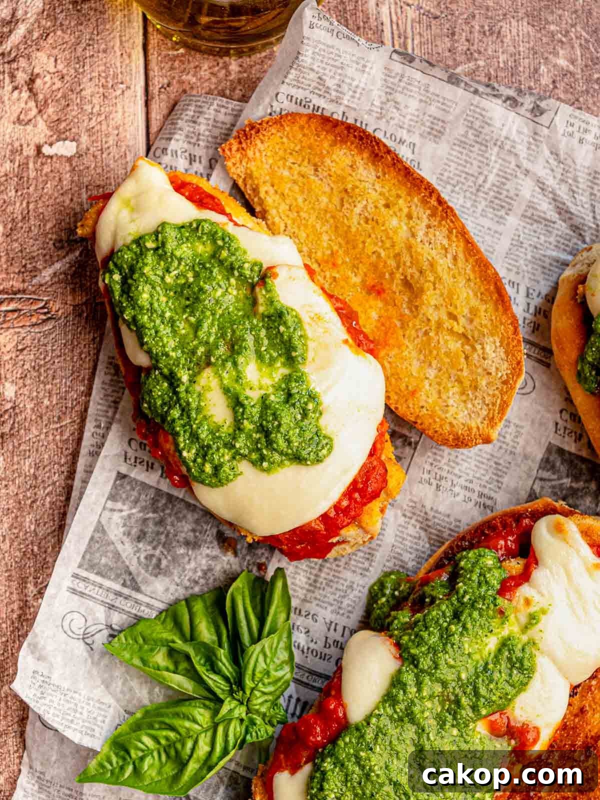 Chicken parm on a sub roll topped with pesto.