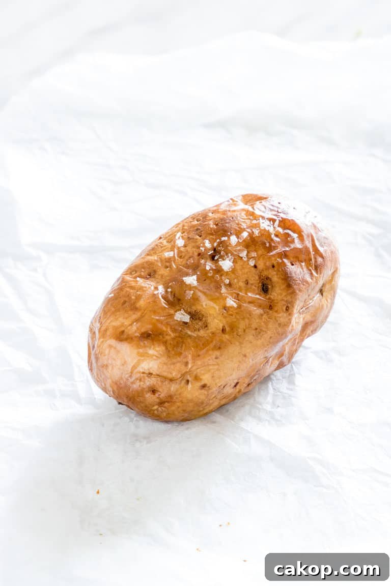Crispy Air Fryer Baked Potatoes Recipe for Perfectly Fluffy Centers 5 one air fryer baked potato sitting on a counter seasoned with oil and salt