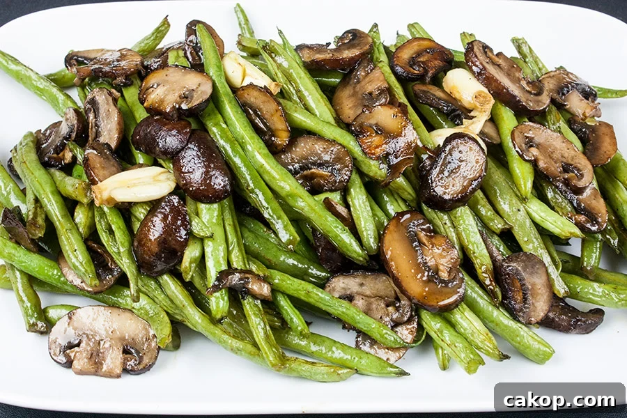 Roasted green beans and mushrooms on a white serving platter.