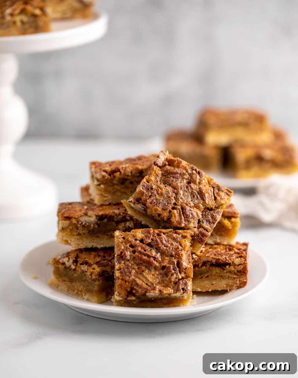 Pecan bars piled on a small white plate.