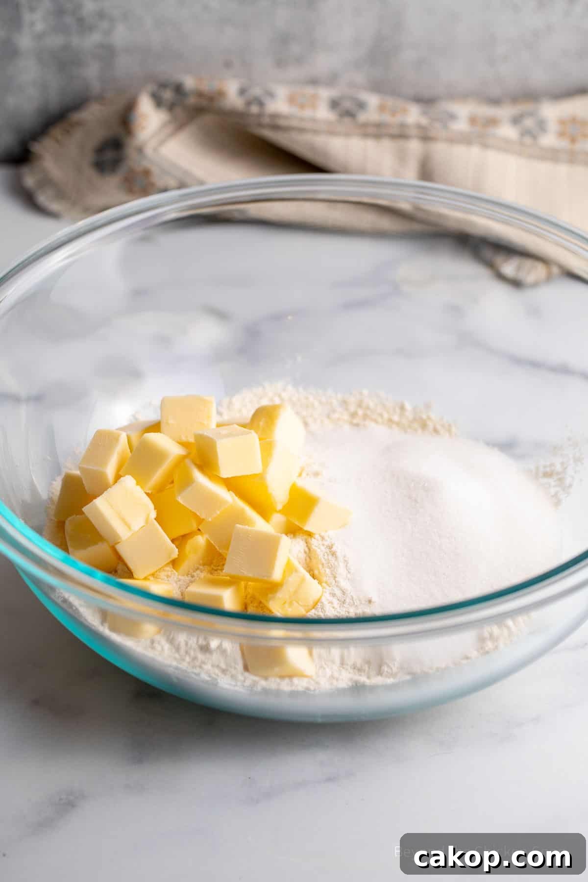 Cubes of butter in a mixing bowl with flour and sugar.