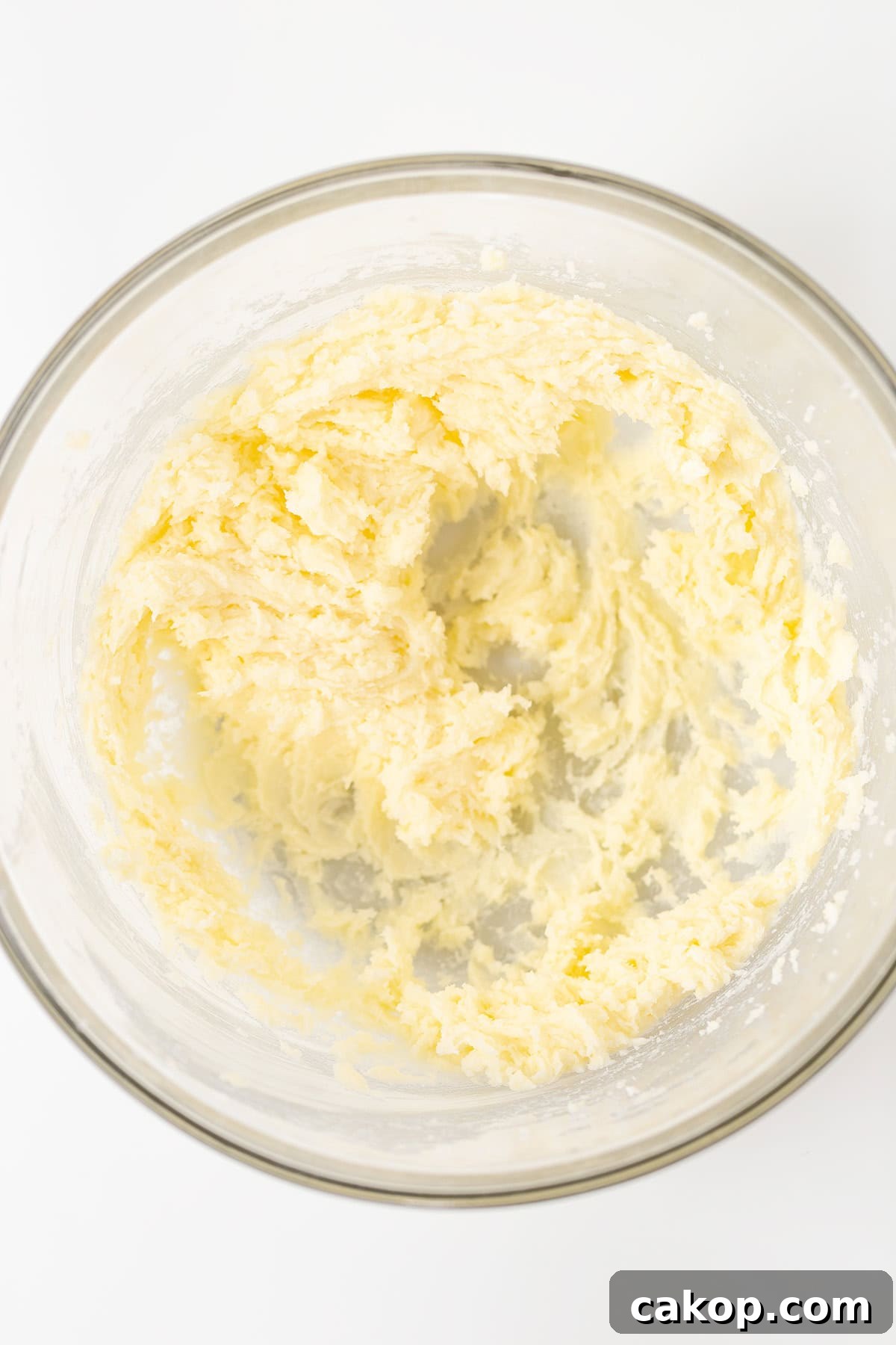 Cookies and Cream Cupcakes Recipe: Rich Oreo-Style Cupcakes 3 A glass bowl containing creamed butter and sugar mixture on a white surface, ready to become the delicious base for Oreo Cookies and Cream Cupcakes.