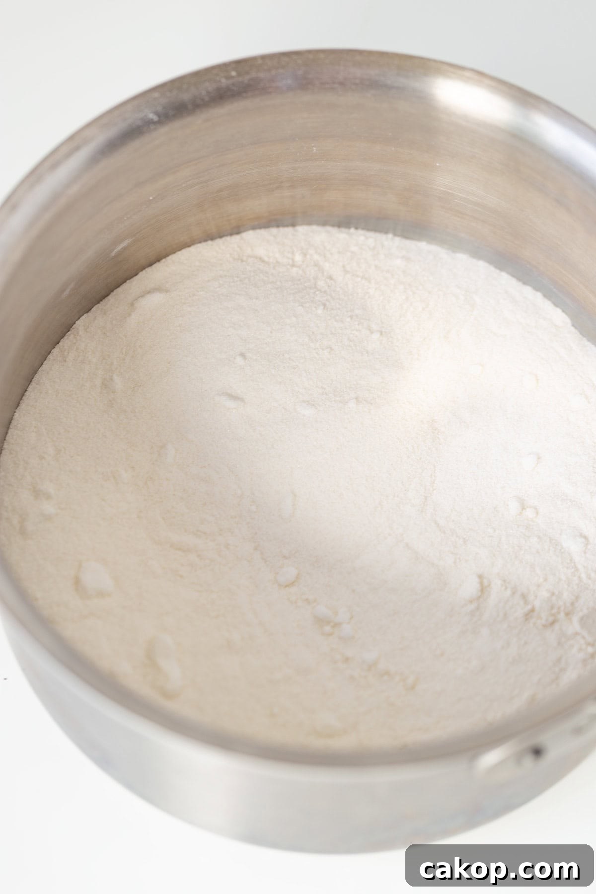 Cookies and Cream Cupcakes Recipe: Rich Oreo-Style Cupcakes 8 A metal mixing bowl filled with a mound of white flour on a white surface, ready to create delicious Oreo Cookies and Cream Cupcakes.