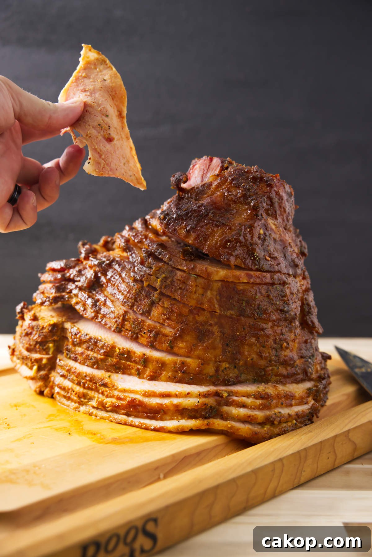 Double-Smoked Ham Recipe: How to Smoke Perfect Ham at Home 2 Holding piece of double smoked ham with spiral ham resting on butcher block.