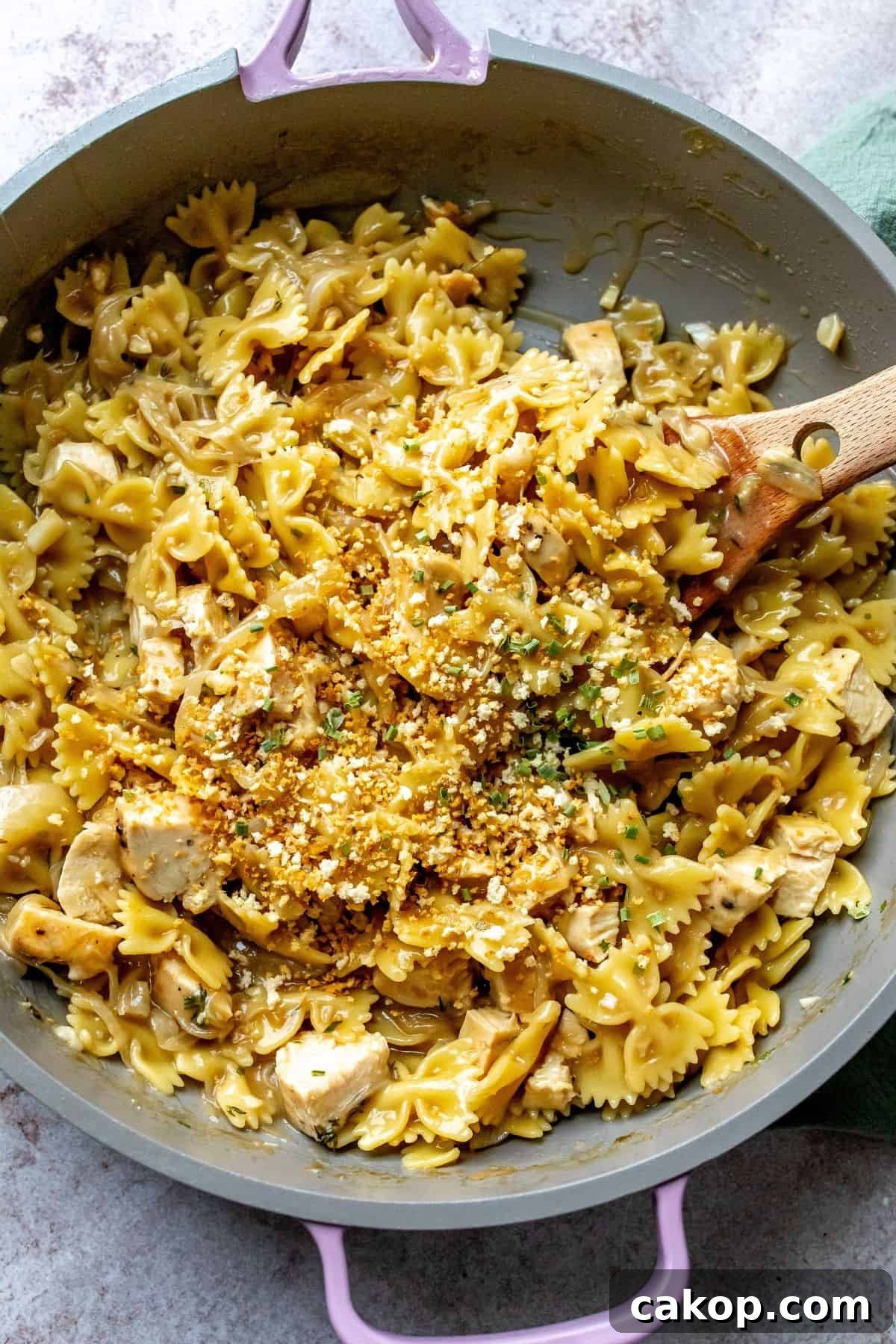 French Onion Pasta Recipe: Creamy Caramelized Onion Noodle Bake 2 Grey and ink skillet with French Onion Pasta in it and a wooden spoon.