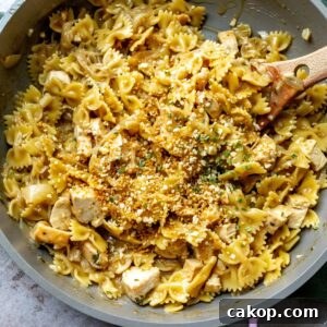 French Onion Pasta Recipe: Creamy Caramelized Onion Noodle Bake 6 Grey and pink skillet with French Onion Pasta in it and a wooden spoon.
